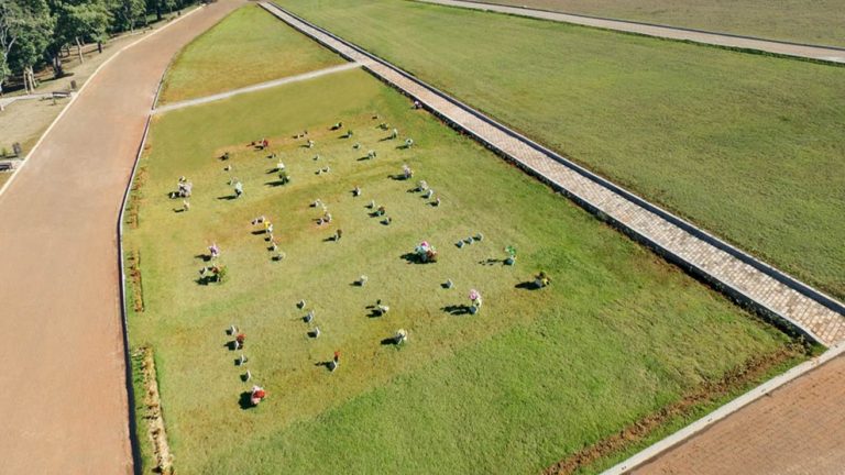 Jazigo familiar em área verde de cemitério arborizado ao pôr do sol